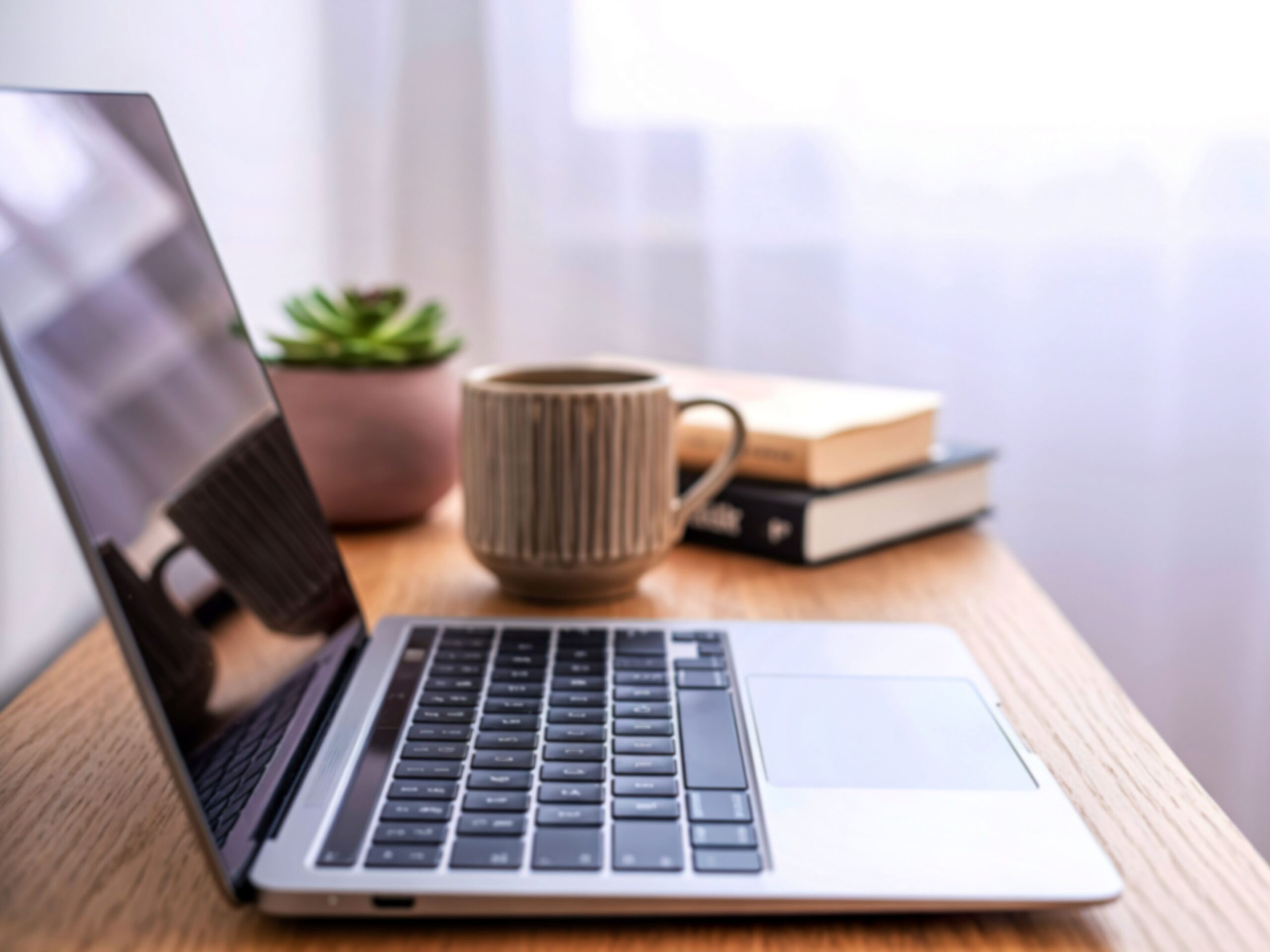 Minimalist desk with open laptop, books, and coffee mug representing focus and productivity