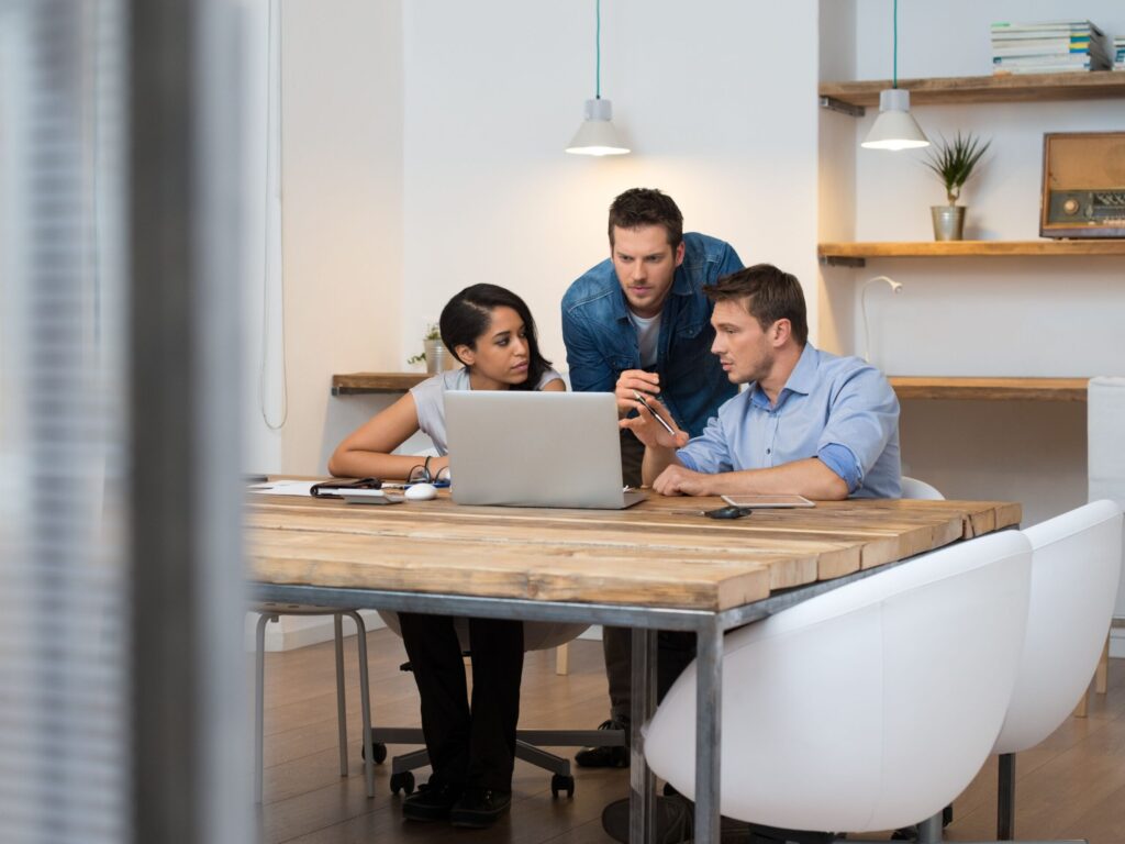 Engineers collaborating at a laptop to solve a project challenge.