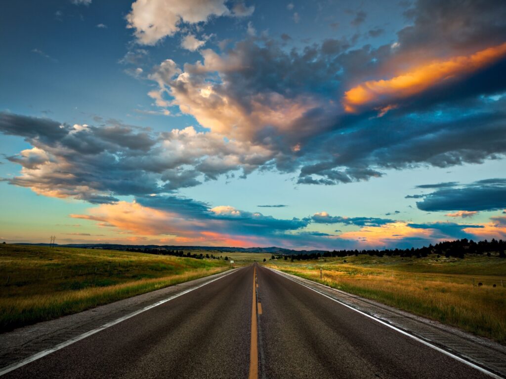 Empty highway stretching into the sunrise symbolizing new opportunities ahead.