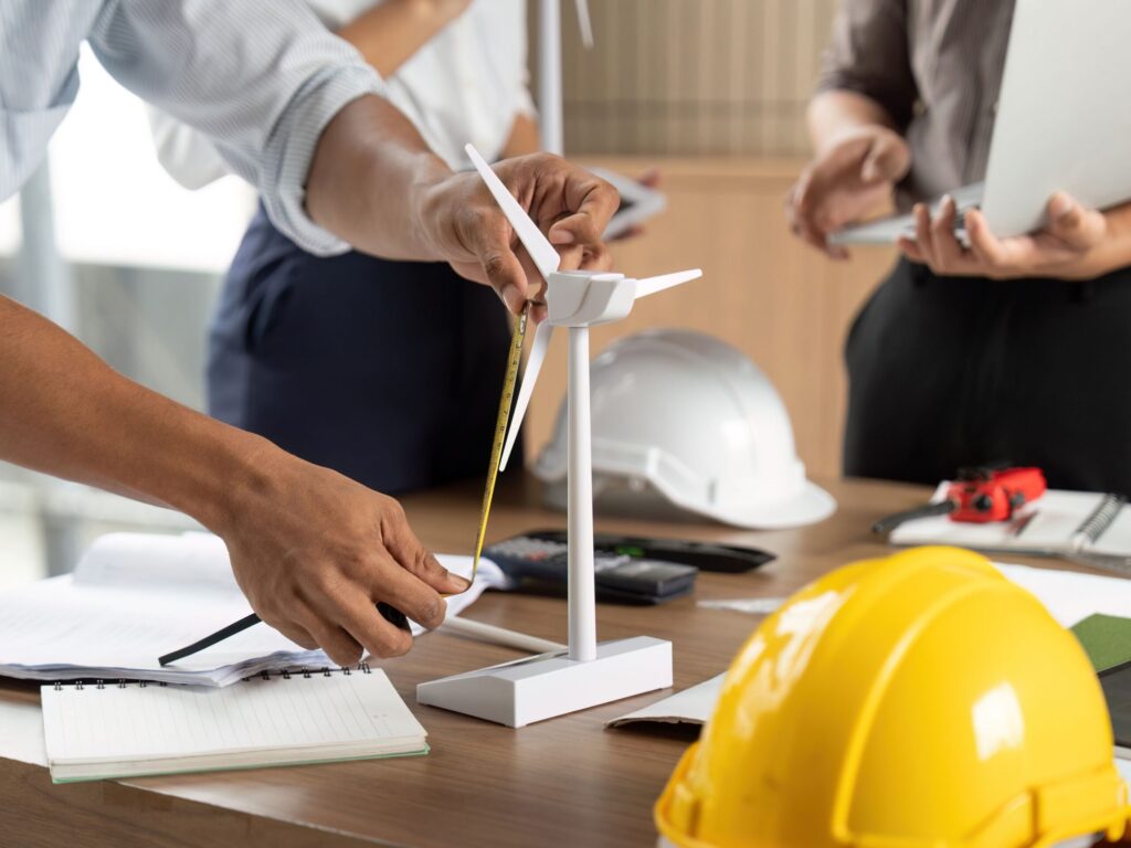 Engineers collaborating on a wind turbine model during a design meeting.