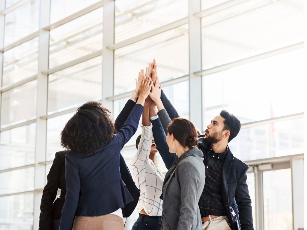 Group of engineers celebrating a successful project with a team high five.